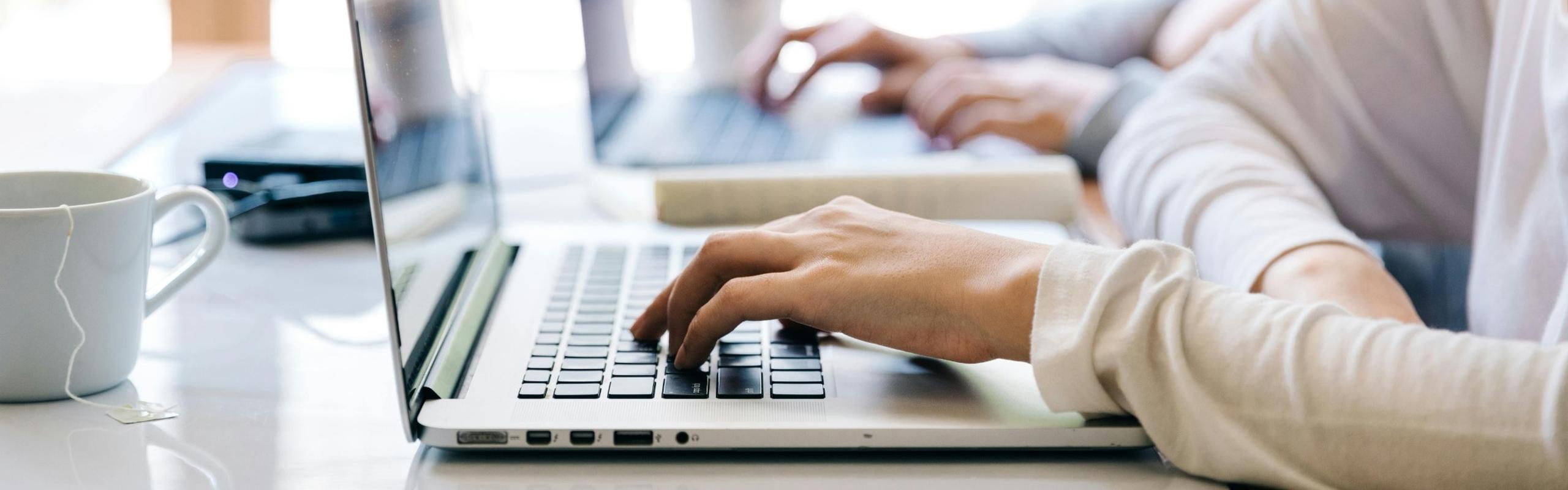 two people typing on laptops